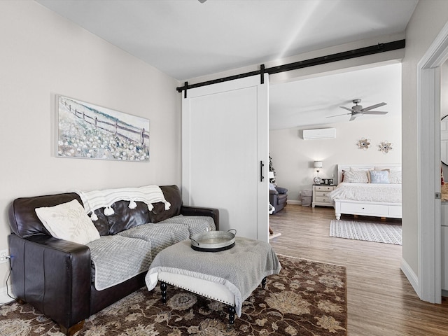 living room with a barn door, ceiling fan, hardwood / wood-style floors, and a wall mounted air conditioner