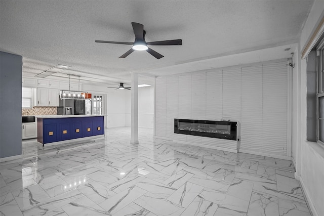 unfurnished living room featuring ceiling fan and a textured ceiling