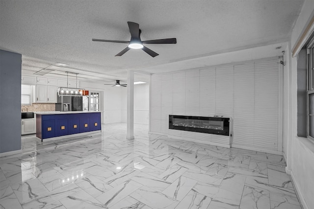 unfurnished living room featuring ceiling fan, a large fireplace, and a textured ceiling