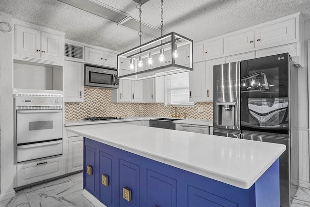 kitchen featuring white cabinetry, sink, stainless steel appliances, decorative light fixtures, and a kitchen island