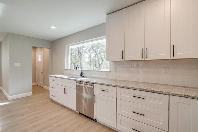 kitchen with sink, light stone counters, stainless steel dishwasher, light hardwood / wood-style floors, and white cabinets