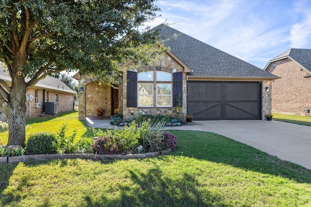 ranch-style home with an attached garage, cooling unit, stone siding, concrete driveway, and roof with shingles