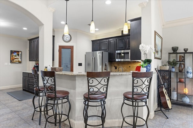 kitchen featuring appliances with stainless steel finishes, arched walkways, backsplash, and a kitchen bar