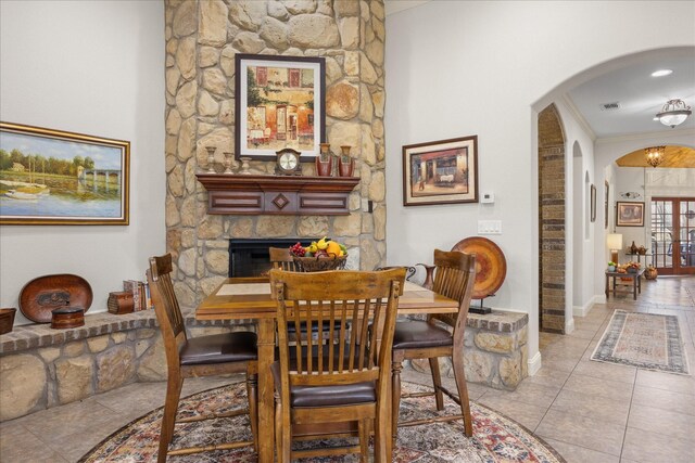 dining room with a fireplace, light tile patterned floors, and ornamental molding