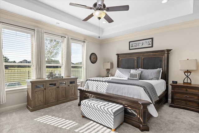 bedroom featuring ceiling fan, light carpet, baseboards, ornamental molding, and a raised ceiling