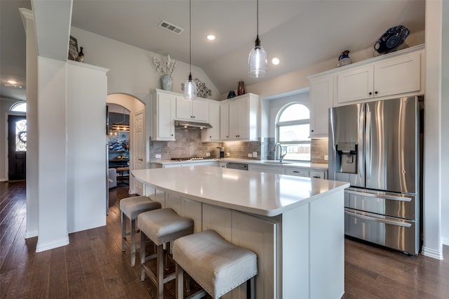 kitchen with sink, a center island, dark hardwood / wood-style flooring, lofted ceiling, and appliances with stainless steel finishes