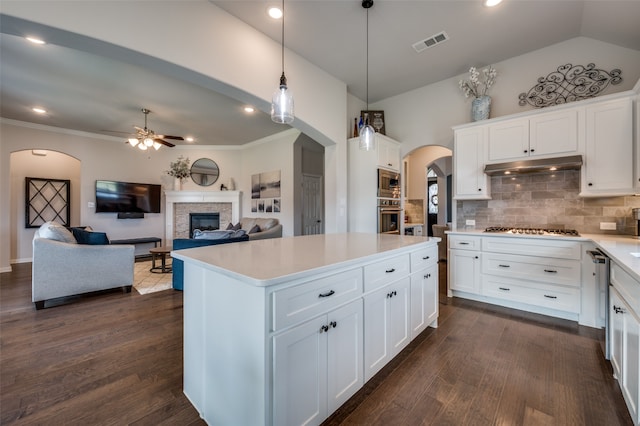 kitchen featuring white cabinets, appliances with stainless steel finishes, dark hardwood / wood-style floors, and a fireplace