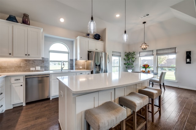 kitchen featuring white cabinetry, a center island, stainless steel appliances, dark hardwood / wood-style floors, and decorative light fixtures