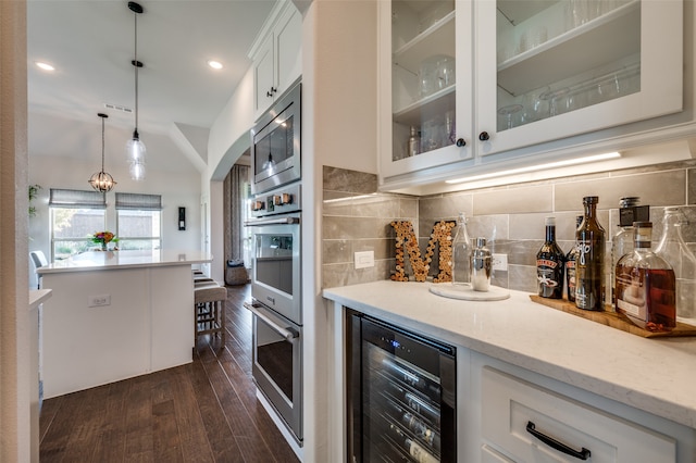 kitchen featuring appliances with stainless steel finishes, beverage cooler, pendant lighting, dark hardwood / wood-style floors, and white cabinetry