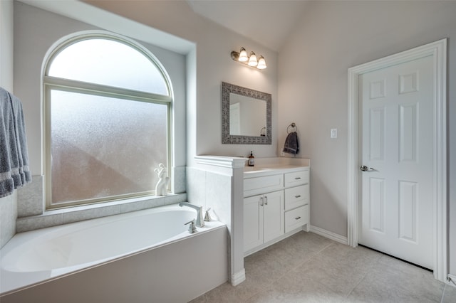 bathroom featuring tile patterned flooring, vanity, a bathtub, and vaulted ceiling