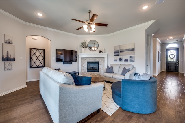 living room with a fireplace, dark hardwood / wood-style flooring, ceiling fan, and ornamental molding