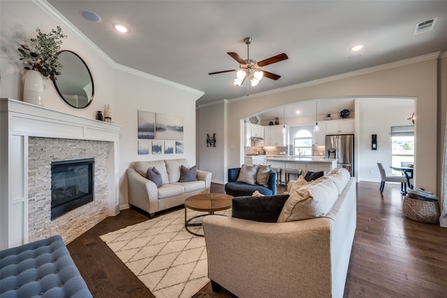 living room with a fireplace, crown molding, and dark wood-type flooring