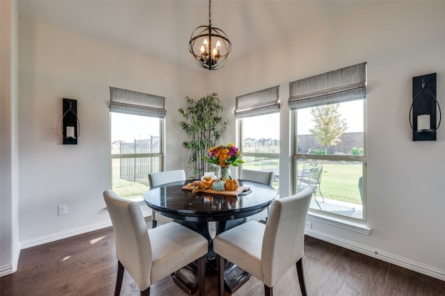 dining space with dark hardwood / wood-style flooring, a wealth of natural light, and an inviting chandelier