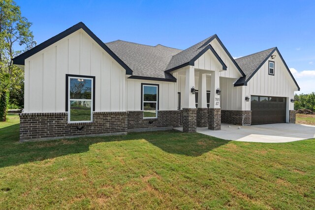 modern farmhouse featuring a front yard and a garage