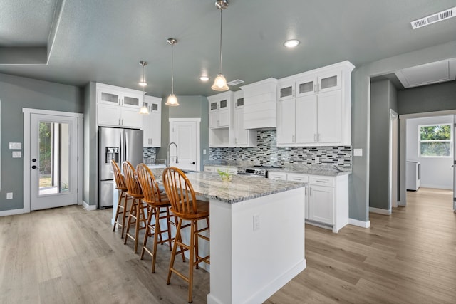 kitchen featuring a wealth of natural light, a center island with sink, white cabinetry, and stainless steel appliances