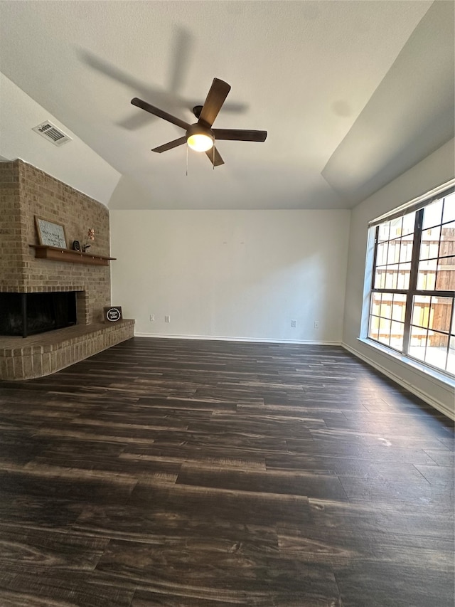 unfurnished living room featuring dark wood-type flooring, ceiling fan, vaulted ceiling, and a brick fireplace