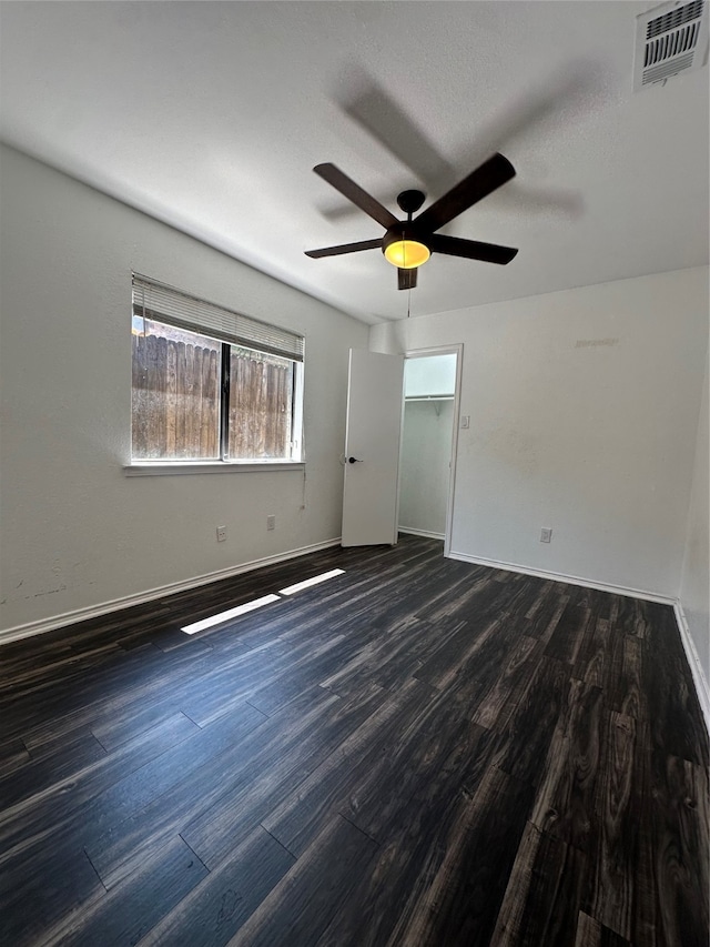 unfurnished bedroom with dark wood-type flooring, a textured ceiling, ceiling fan, and a closet