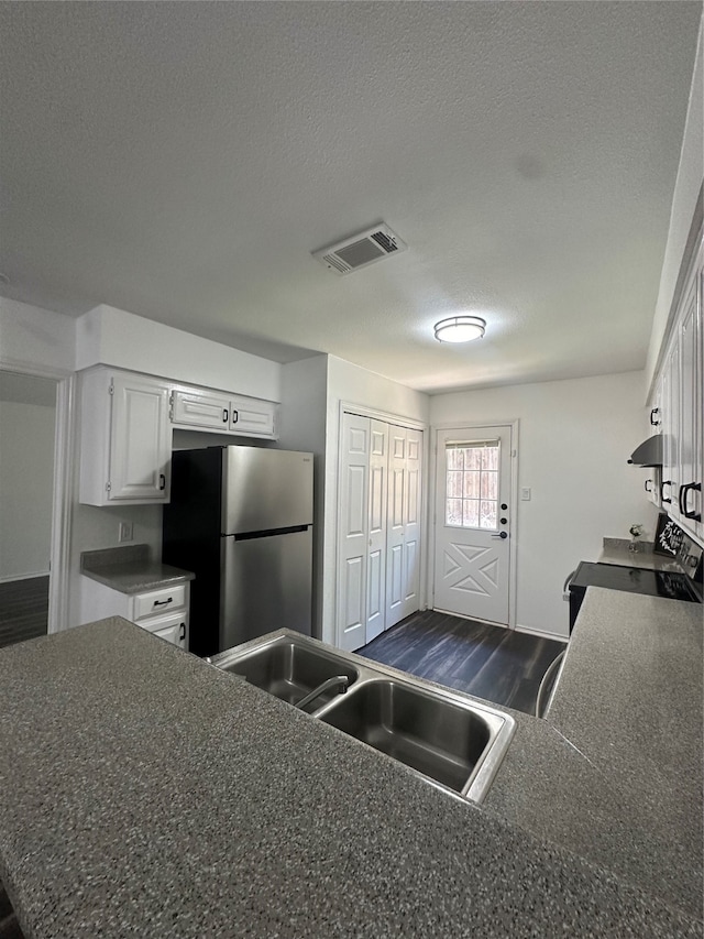 kitchen with white cabinetry, stainless steel fridge, sink, and a textured ceiling