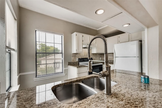 kitchen featuring backsplash, white cabinets, white refrigerator, range with electric stovetop, and light stone countertops