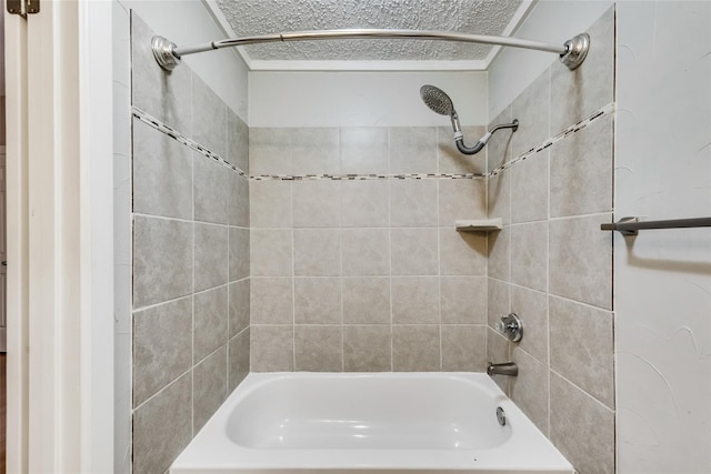 bathroom featuring a textured ceiling and tiled shower / bath