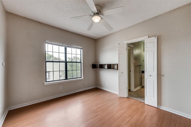 empty room with ceiling fan, light hardwood / wood-style floors, and a textured ceiling