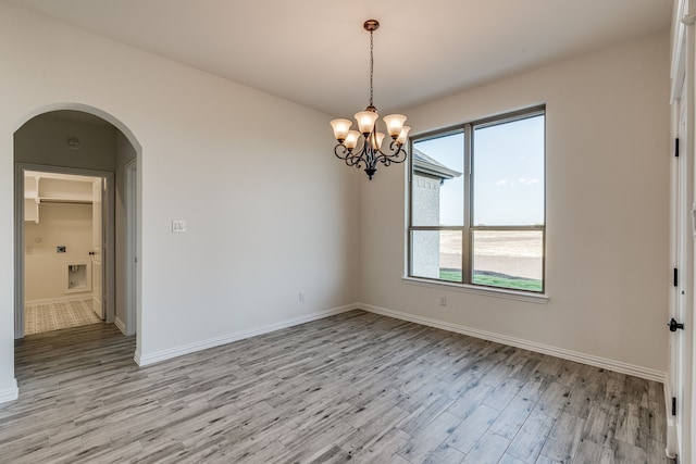 empty room featuring light hardwood / wood-style flooring and an inviting chandelier