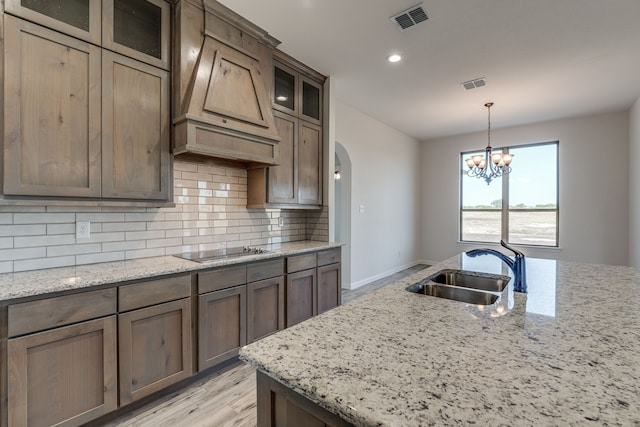 kitchen with black electric cooktop, light stone counters, sink, and decorative backsplash