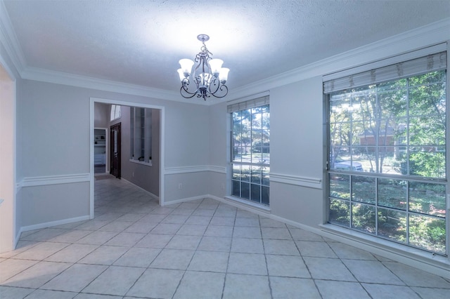 tiled empty room featuring crown molding, a textured ceiling, and a notable chandelier