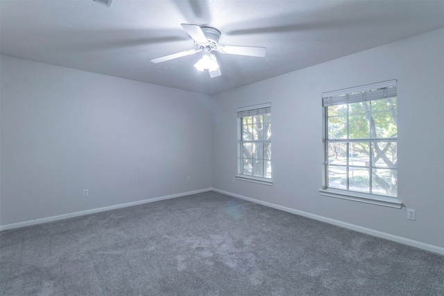 unfurnished room with dark colored carpet and ceiling fan