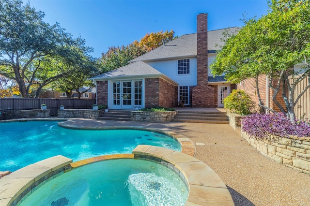 view of swimming pool with french doors and an in ground hot tub