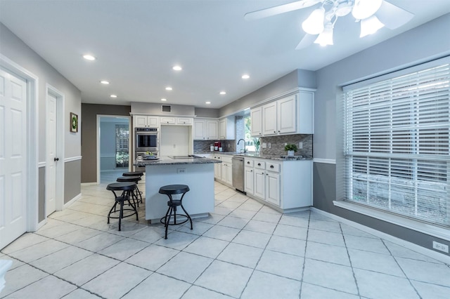 kitchen with appliances with stainless steel finishes, a breakfast bar, a kitchen island, and dark stone countertops