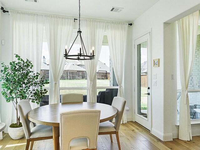 dining room with light wood-type flooring and a notable chandelier