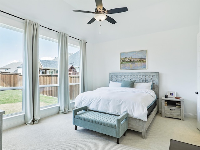 bedroom with multiple windows, ceiling fan, and light colored carpet