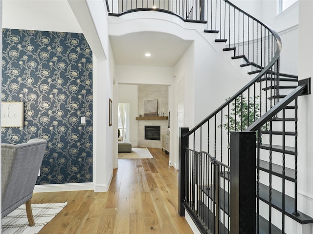 foyer with light hardwood / wood-style floors, a high ceiling, and a tiled fireplace