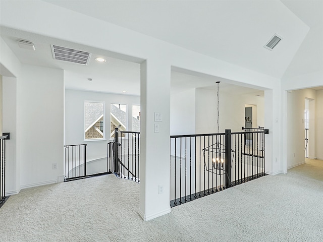 hall featuring carpet, lofted ceiling, and an inviting chandelier