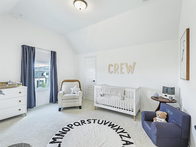 carpeted bedroom featuring a nursery area and lofted ceiling