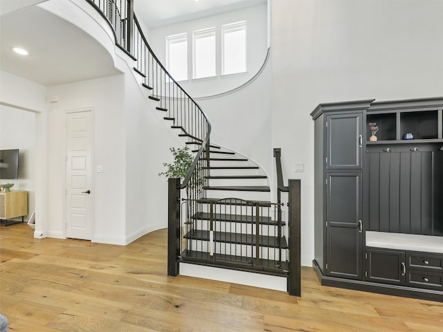 staircase featuring hardwood / wood-style flooring and a towering ceiling