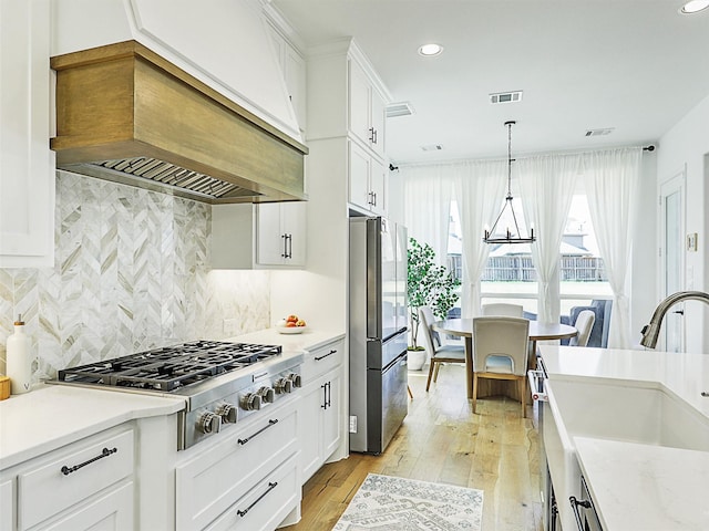 kitchen featuring sink, custom exhaust hood, white cabinets, and appliances with stainless steel finishes