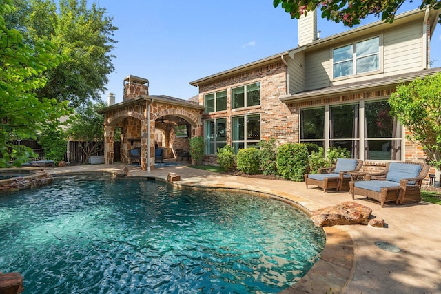 view of pool featuring a fireplace and a patio