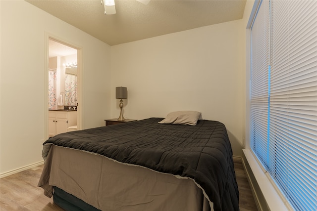 bedroom with a textured ceiling, connected bathroom, light hardwood / wood-style floors, and ceiling fan