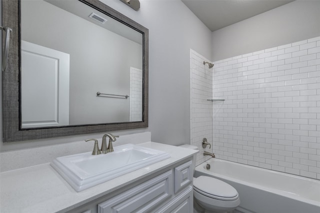 full bathroom with tiled shower / bath, vanity, and toilet