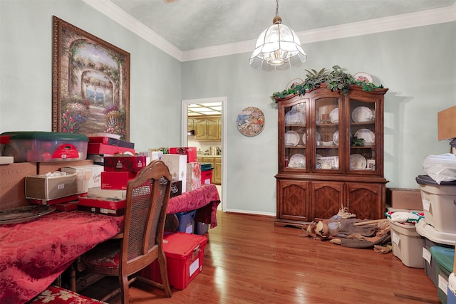 dining room with hardwood / wood-style floors, crown molding, and an inviting chandelier