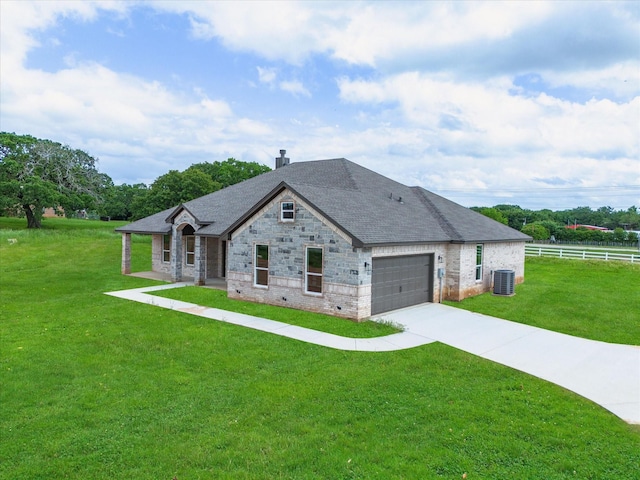 french country home featuring a garage, a front lawn, and central air condition unit