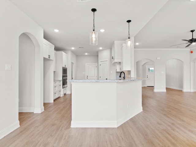 kitchen featuring light stone countertops, sink, backsplash, decorative light fixtures, and white cabinets