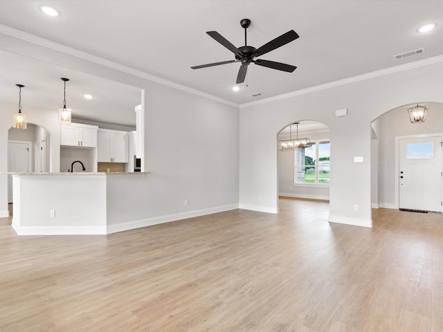 unfurnished living room featuring ceiling fan with notable chandelier, light hardwood / wood-style floors, ornamental molding, and sink