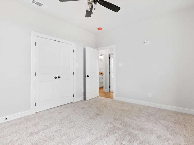 unfurnished bedroom featuring ceiling fan, light colored carpet, and a closet