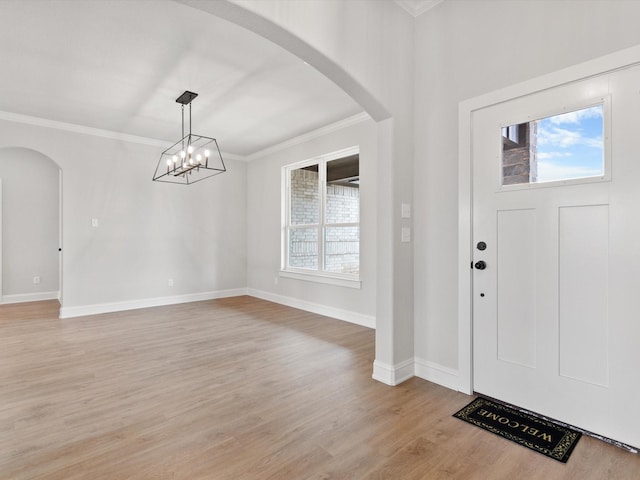 foyer with a chandelier, light wood-type flooring, and crown molding