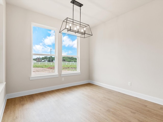 unfurnished dining area with light hardwood / wood-style flooring and a notable chandelier