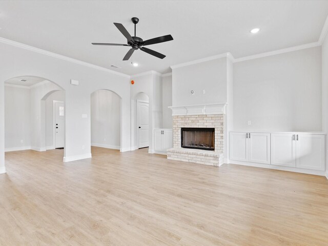 unfurnished living room featuring hardwood / wood-style floors, ceiling fan, ornamental molding, and a brick fireplace