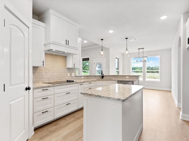 kitchen with tasteful backsplash, white cabinets, light hardwood / wood-style floors, a kitchen island, and hanging light fixtures